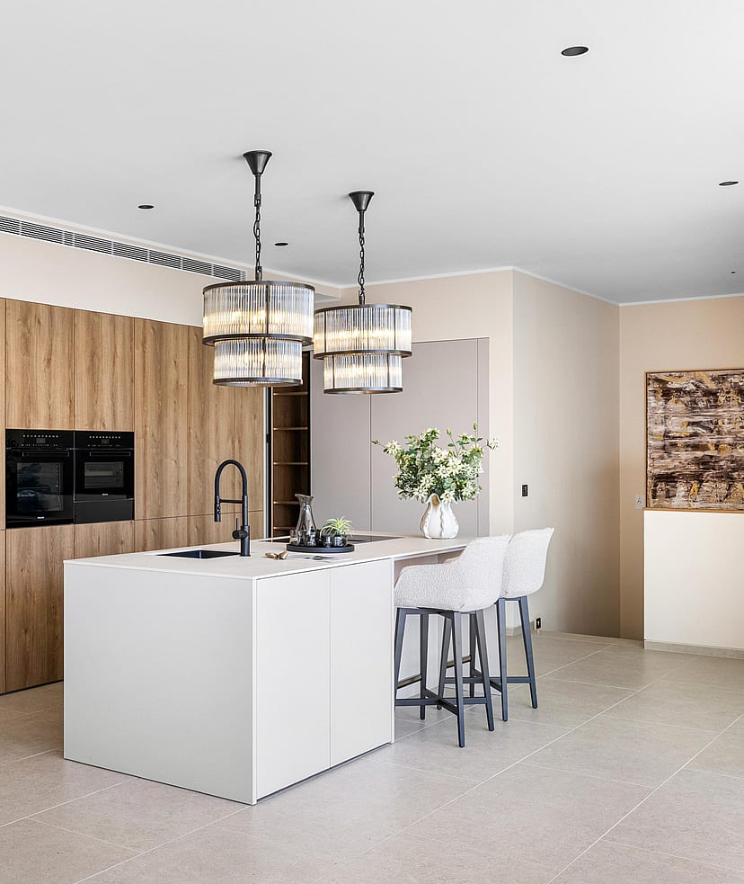 Fitted kitchen with full-height oak cabinetry, white composite island and two black-frame pendant lights