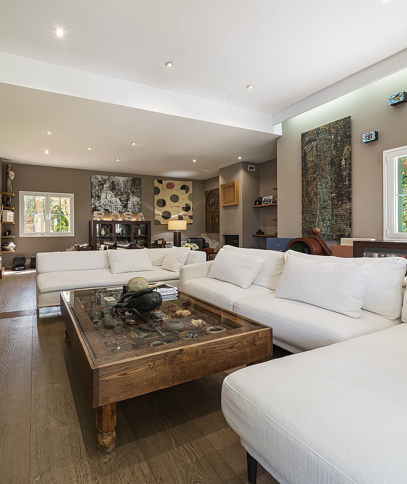 Spacious living room featuring white modular sofas, a stone-topped coffee table, and beige tiled floors under recessed lighting.