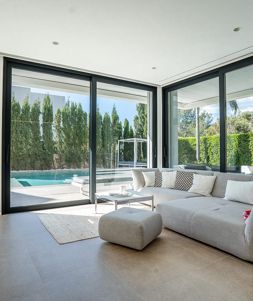 Living area with grey sectional sofa and sliding glass doors opening onto the swimming pool.