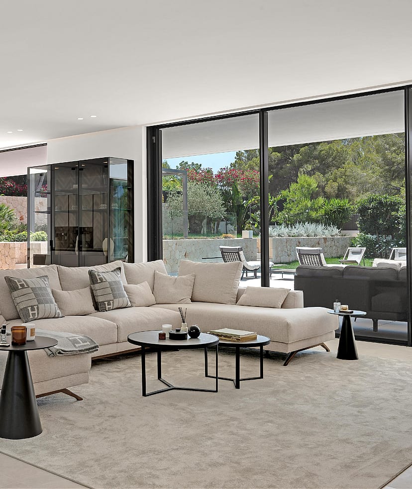 Open-plan living room with large sectional sofa, dining table and floor-to-ceiling glazing to garden