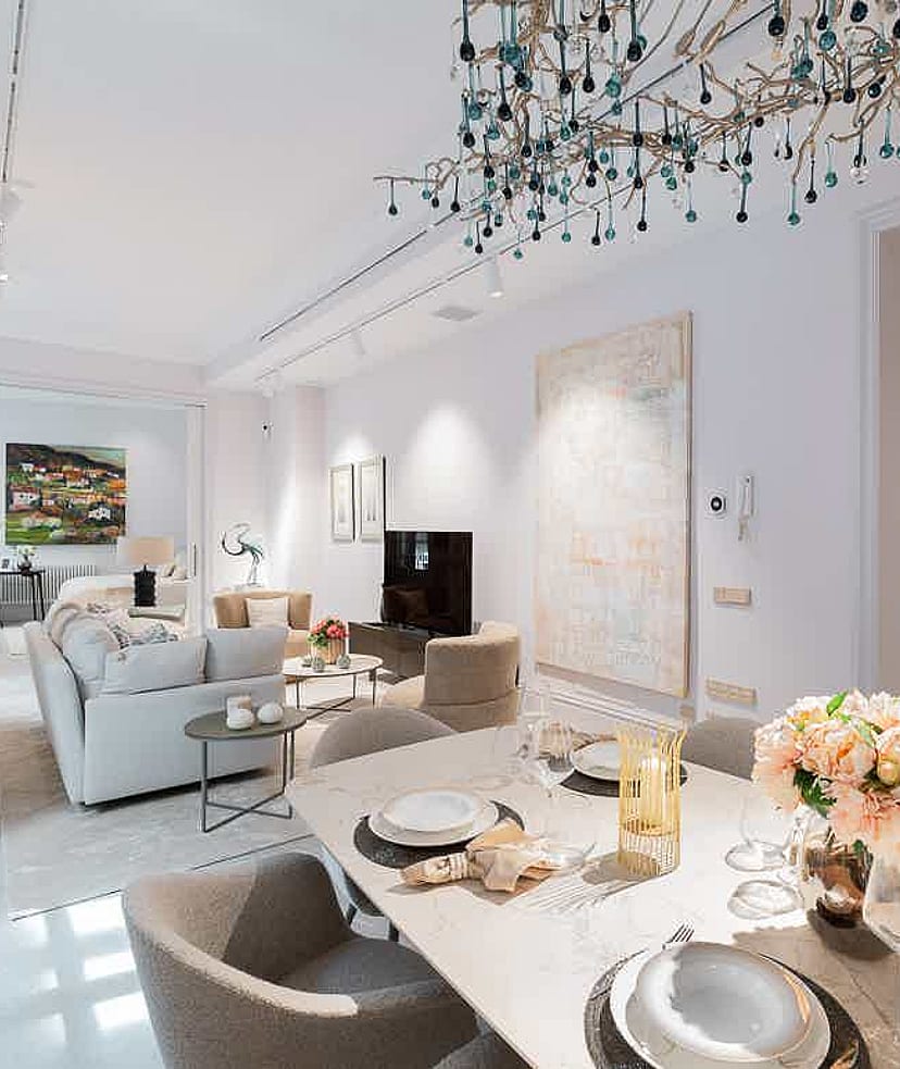 Bright open-plan living area featuring a modern dining set with upholstered chairs and a sofa area with neutral textiles.
