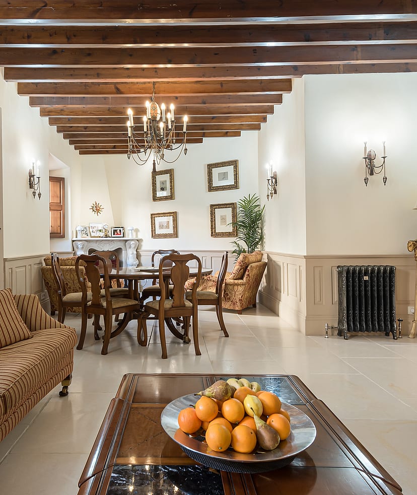 Living and dining area with striped sofa, wooden dining table and beamed ceiling