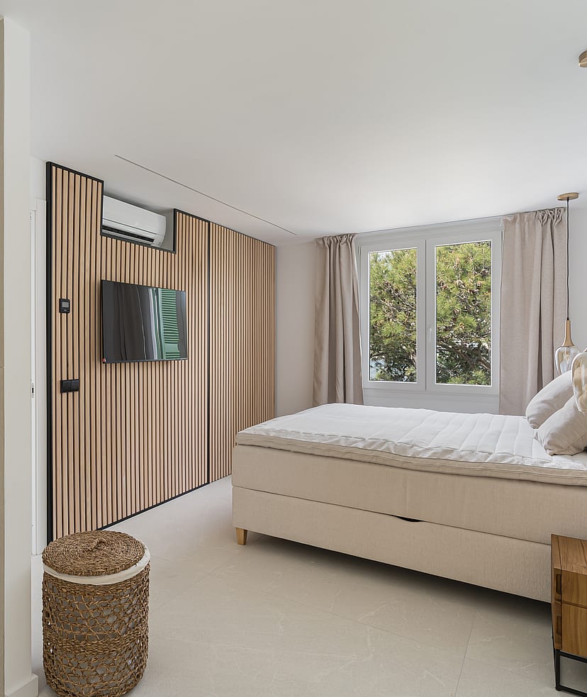 Contemporary bedroom featuring a vertical wood slat wall, upholstered bed, glass pendant lights, and garden views.