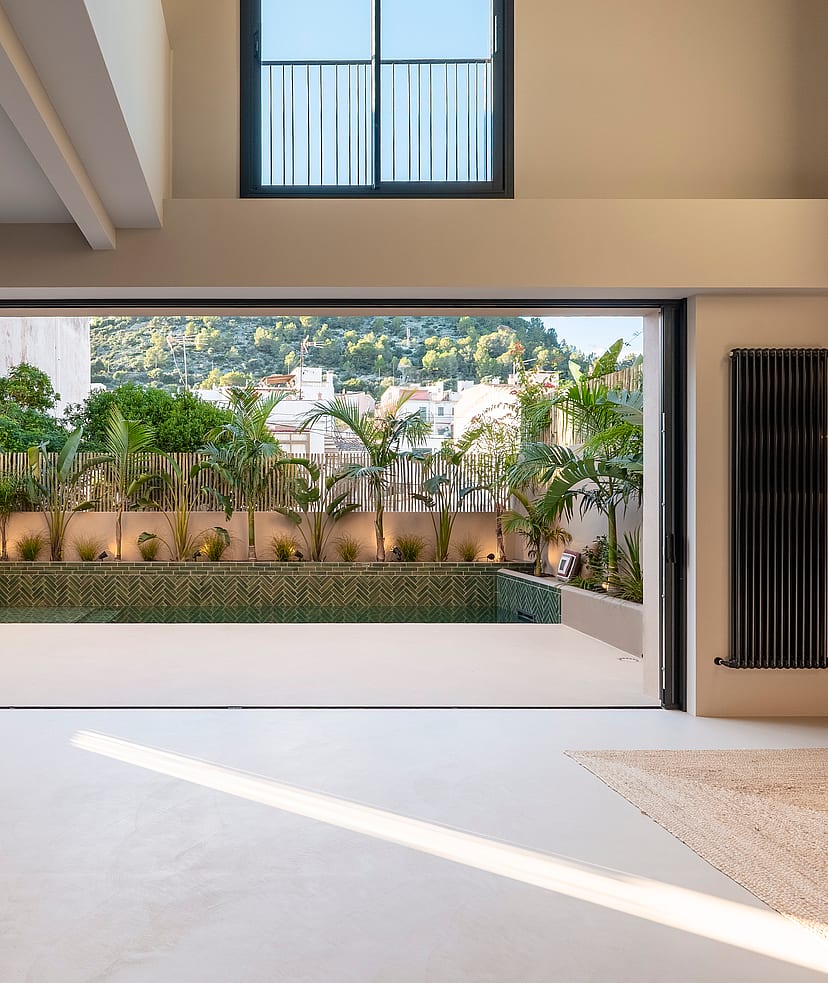 Open-plan living space featuring full-width sliding doors that lead to a private terrace with a pool and mountain views.
