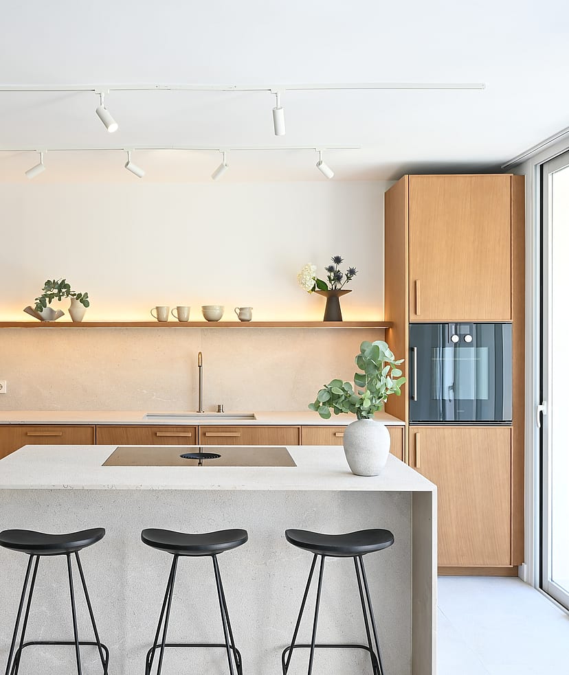Open-plan kitchen in oak and Binissalem marble with sculptural concrete staircase and Zarci stone floors