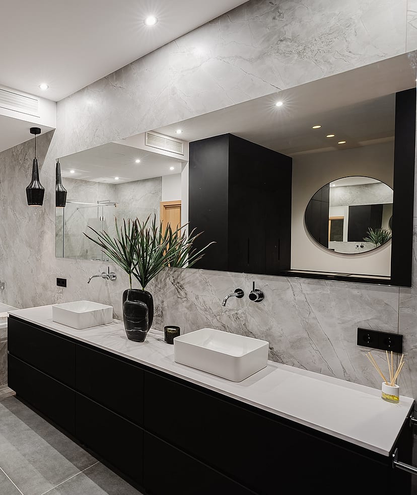 Modern bathroom featuring gray marble walls, a black floating vanity with double sinks, and a glass-enclosed walk-in shower.