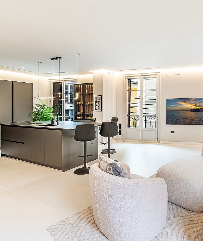 Modern open-plan living space with a dark island kitchen, textured white seating, and high ceilings in an Old Town apartment.