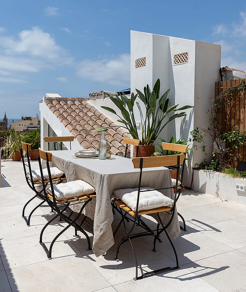 Rooftop terrace featuring an outdoor dining table, potted greenery, and views towards the Santa Eulàlia Church tower.
