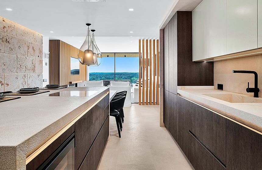 Modern kitchen with dark wood cabinetry, a stone kitchen island, and a clear view towards mountain scenery in Santa Ponsa.