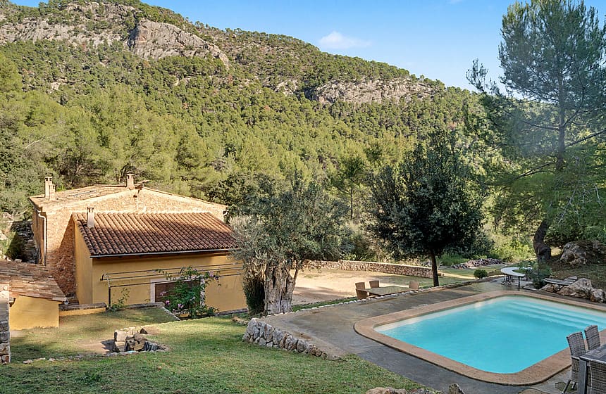 Swimming pool and garden with mountain and pine forest behind a rustic finca