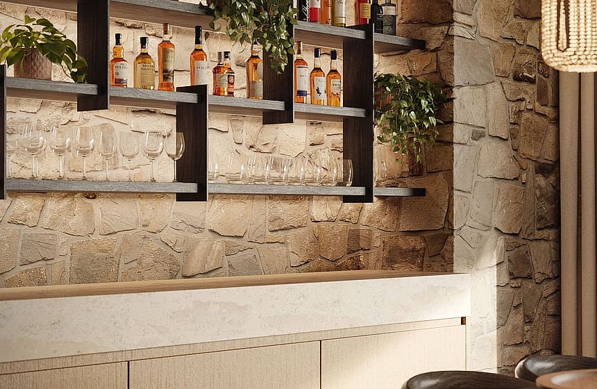 A dining space featuring a textured natural stone wall with built-in metal shelving displaying spirits and glassware above a light wood paneled bar counter.