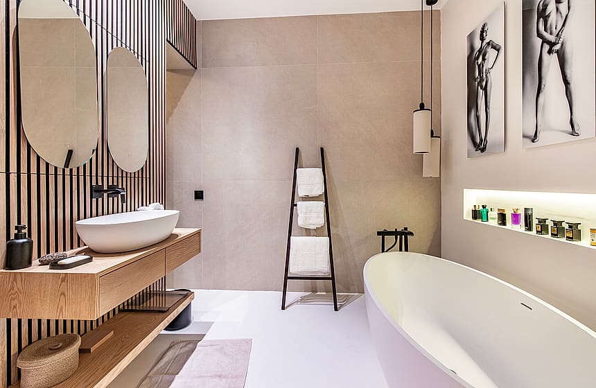 Modern bathroom featuring a white freestanding bathtub, wooden slatted feature wall, vessel sink, and minimal lighting.