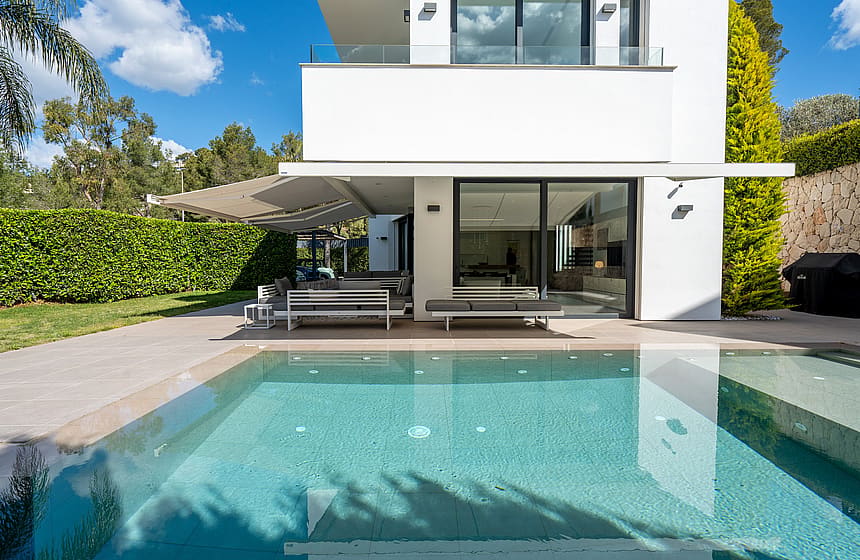 Exterior view of the villa featuring a saltwater infinity pool, covered terrace, and direct access to the living area.