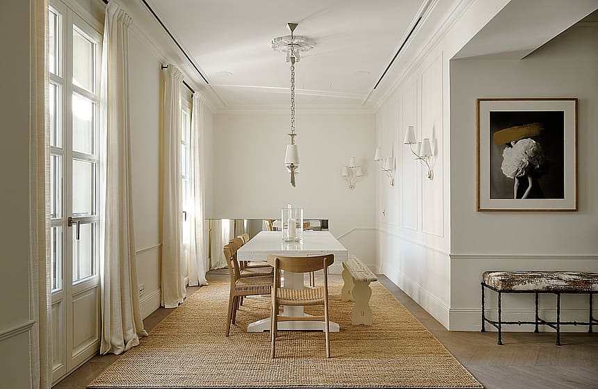 Expansive dining gallery with high ceilings, wooden floor, natural linen seating, windows along full length, and jute rug