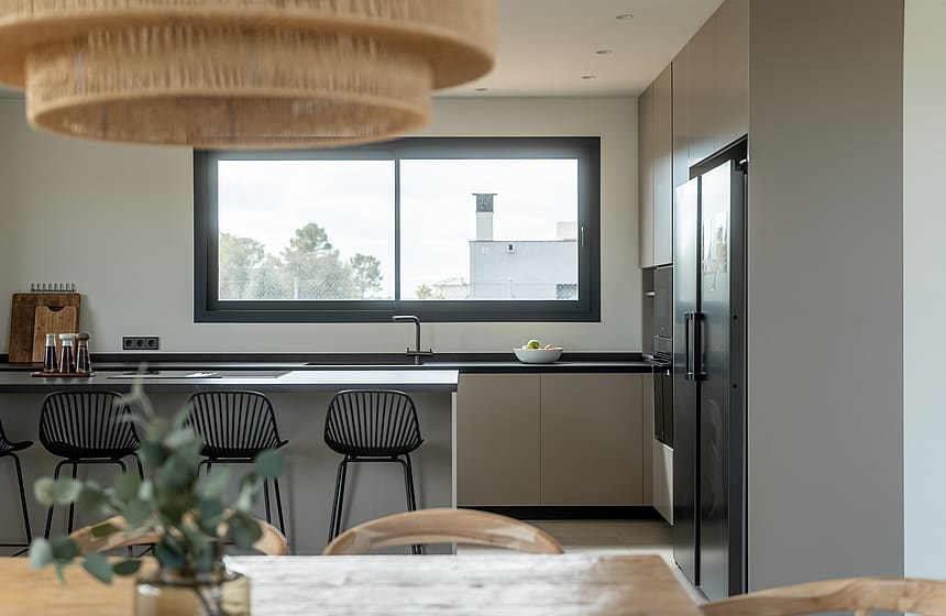 Contemporary kitchen featuring a grey island with black bar stools, dark countertops, and a wide window with mountain views.