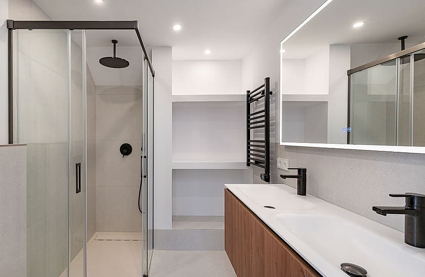 Contemporary bathroom with walk-in glass shower, wall-mounted matte black fixtures, and a wooden double vanity.