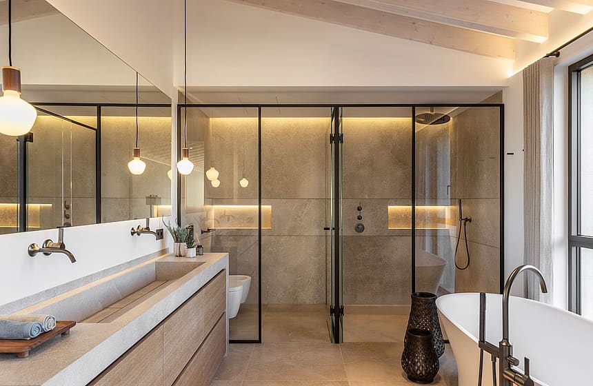 Modern bathroom featuring a double vanity with stone basin, a walk-in glass shower, and a freestanding white bathtub.