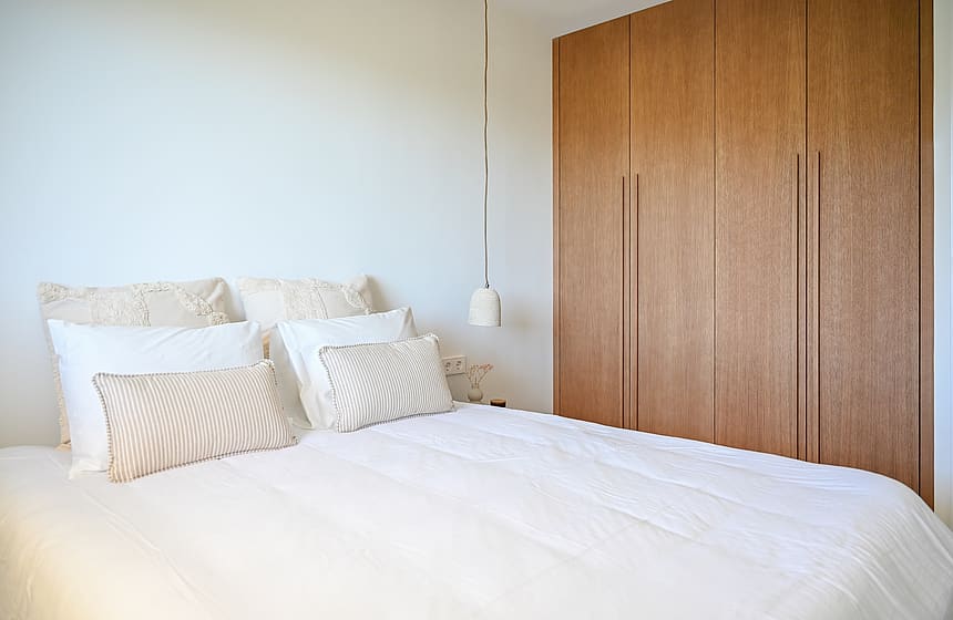 Guest bedroom with caramel linen bedding, oak low shelving beneath eaves, and minimalist Nordic styling