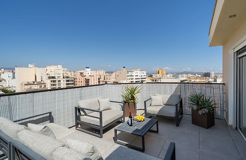 Rooftop terrace featuring outdoor sofas and a coffee table with expansive views over the Old Town city skyline.