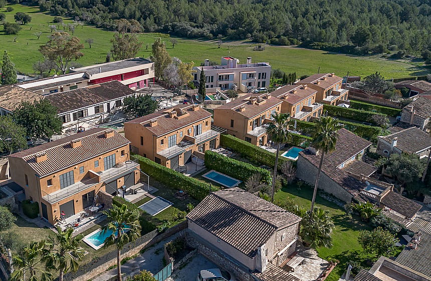 Aerial perspective of a cluster of terracotta-roofed townhouses with private pools and landscaped gardens in Es Capdella.