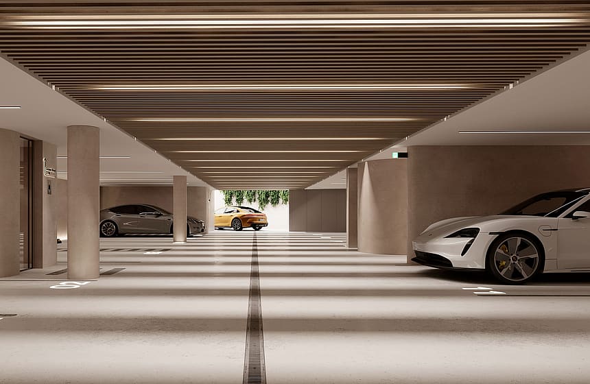 A modern, well-lit subterranean parking garage with concrete columns, linear ceiling lighting, and marked parking spaces.