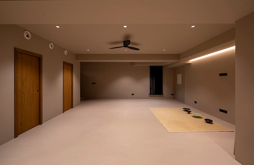 Minimalist multi-purpose room with grey walls, wooden doors, and integrated warm LED lighting.