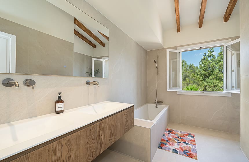 Contemporary bathroom featuring a long oak vanity with double sinks and wall-mounted brushed metal faucets.