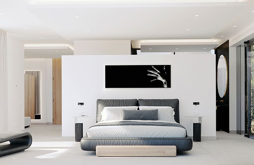 Modern bedroom with a gray upholstered bed and white walls. To the right, a circular mirror marks the en-suite entrance.