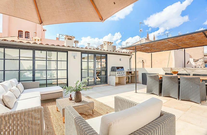 A spacious rooftop terrace in an Old Town townhouse features wicker seating, a dining area, and a built-in outdoor kitchen.