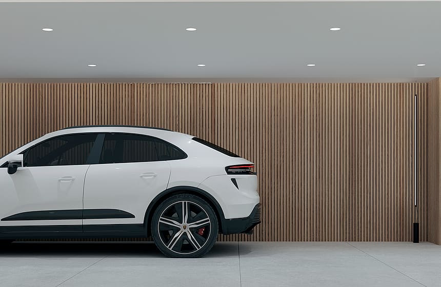 A white car parked in a garage featuring floor-to-ceiling vertical oak wood slats on the back wall and light grey tiled floors.