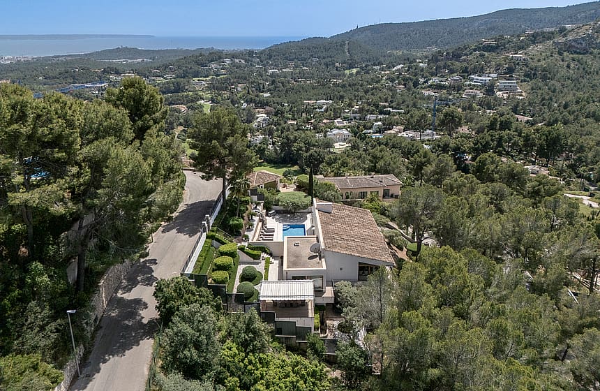 Elevated view from Son Vida villa across green pine-covered hillside toward Palma Bay and the Mediterranean