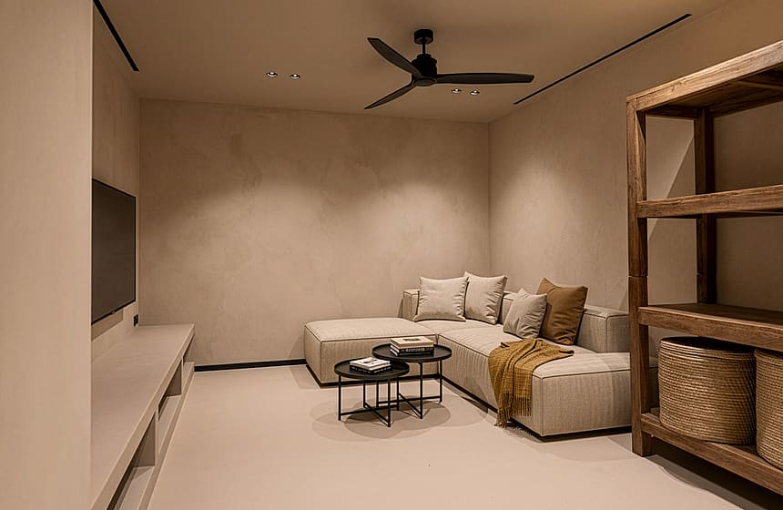 A minimalist living room with a beige sectional sofa, a low white console, and a wooden storage unit under a ceiling fan.