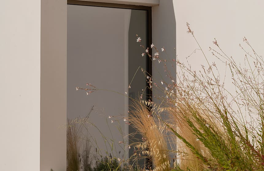 A close-up of a contemporary building exterior with geometric stone panels and a vertical recessed glass window.