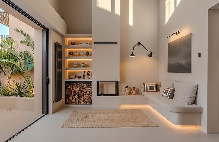 Living room featuring a recessed fireplace, built-in banquette seating, and sliding glass doors to a leafy courtyard.
