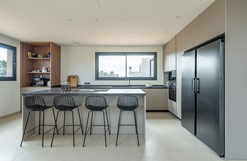 Modern open kitchen with light grey cabinetry, black refrigerator, and a central island with four black wire stools.