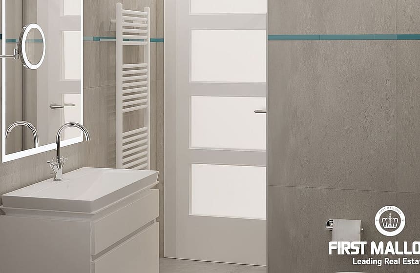 A modern bathroom featuring grey tiled walls, a white floating vanity, a backlit mirror, and a wall-mounted towel rail.