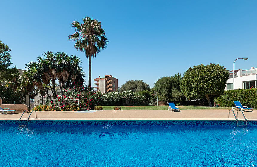 Gemeinschaftlicher Außenpool mit Palmen und blühendem Garten in einem Wohngebäude in Bonanova Palma
