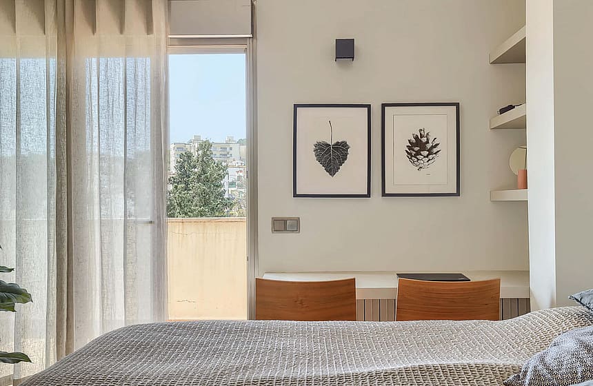 Bedroom featuring a double bed, integrated desk space, and sheer curtains leading to a terrace with exterior view.