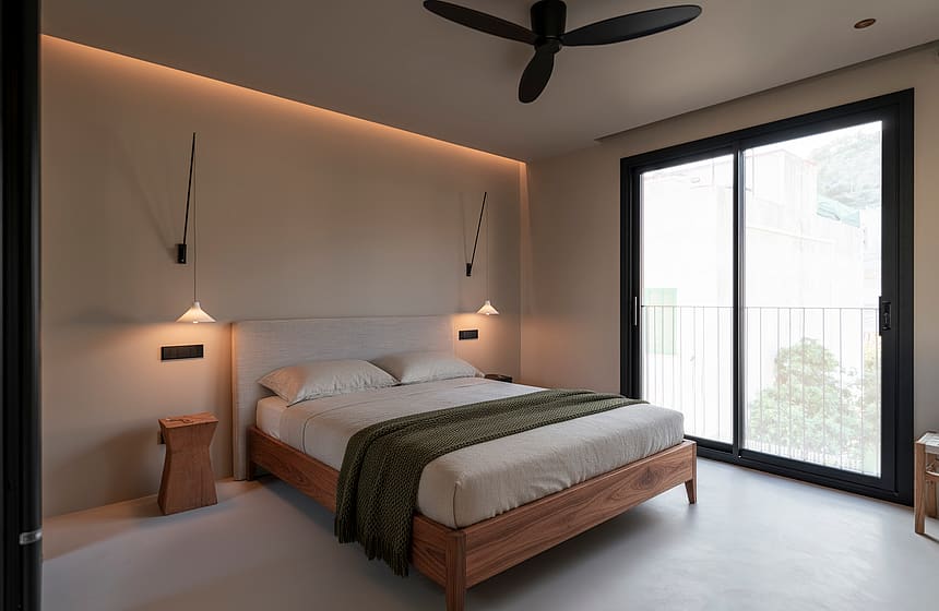 Minimalist bedroom featuring a wooden bed frame, floor-to-ceiling glass doors, and recessed ceiling lighting.