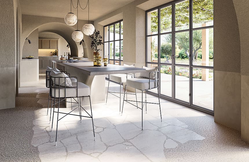 A bright kitchen area with arched stone ceilings, stone floors, and black-framed glass doors leading to a garden.