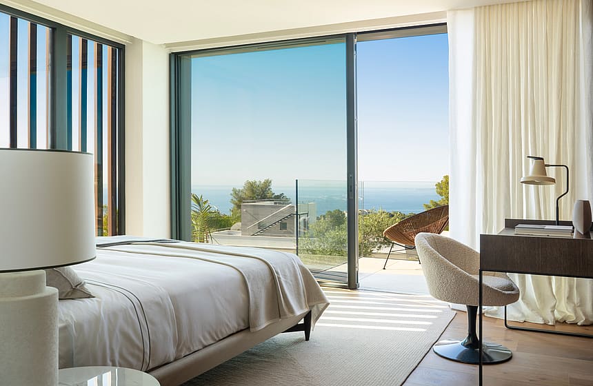 Master bedroom featuring a double bed, modern desk, and floor-to-ceiling windows overlooking the sea.