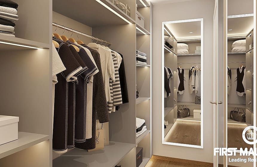 A modern walk-in wardrobe featuring hanging rails, open shelving, and a full-length mirror with LED perimeter lighting.