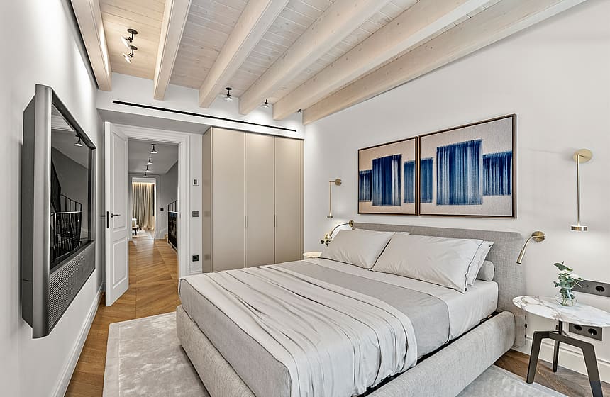 Contemporary bedroom featuring white-painted ceiling beams, light oak floors, built-in wardrobes, and a wall-mounted TV.