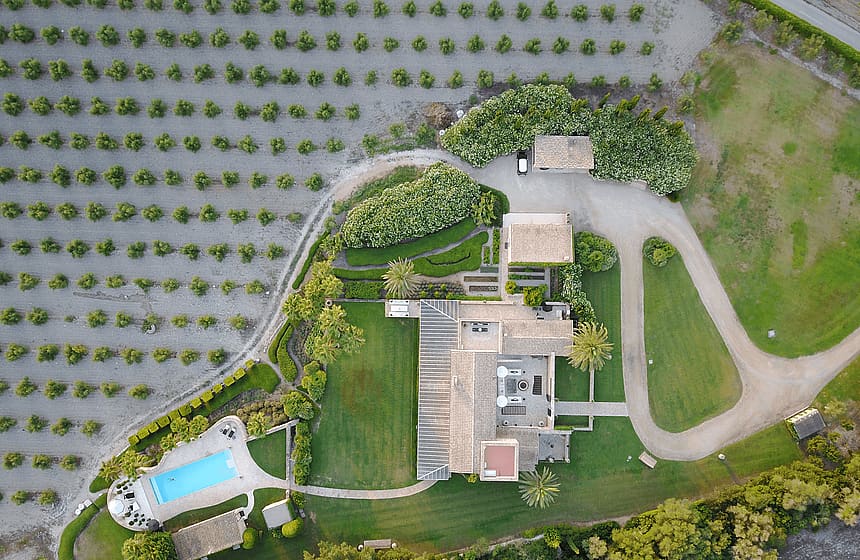 Top-down drone view of a rural estate in Algaida, featuring a main house, swimming pool, and surrounding orchard rows.