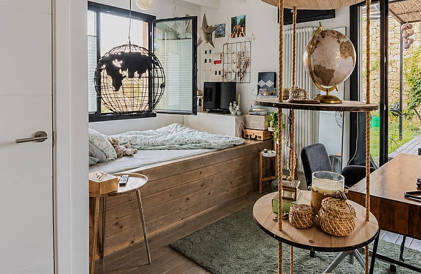 Bedroom with a built-in wooden platform bed, hanging circular shelving unit, and wide-plank wood flooring.
