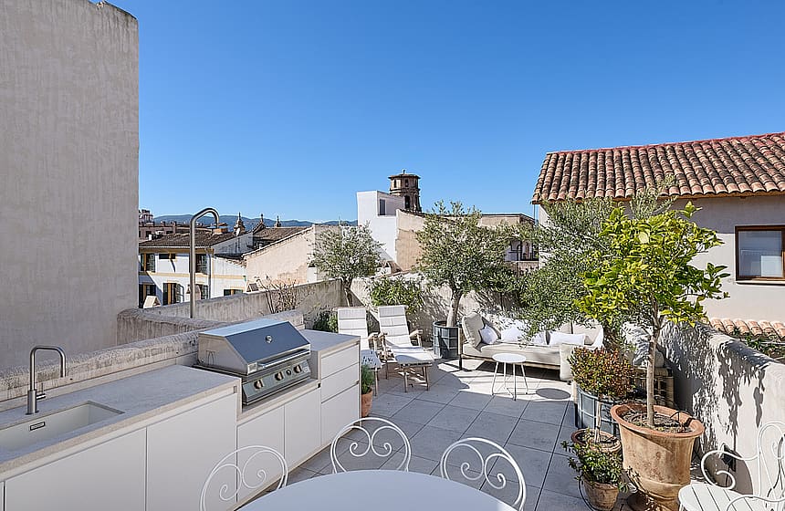 Sunny terrace featuring an outdoor kitchen, barbecue, lounge area, and views of the Old Town rooftops.