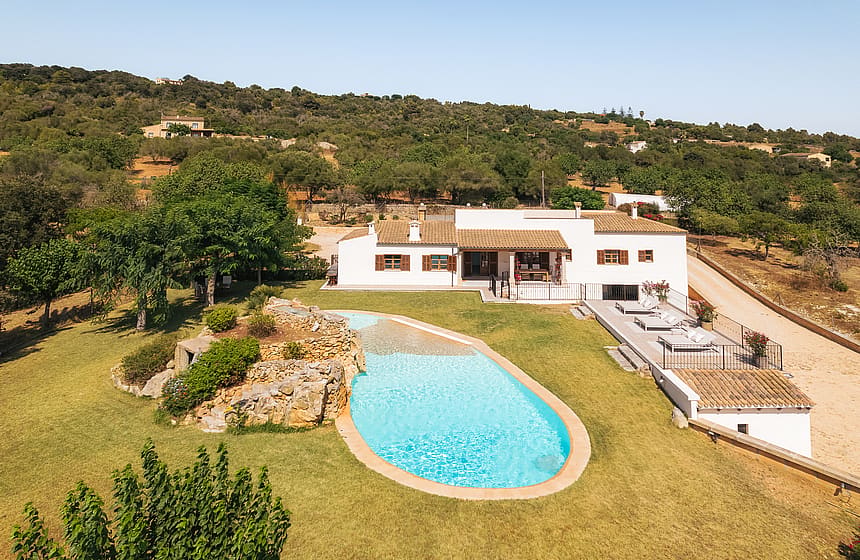 Vista aérea de finca en Manacor con piscina turquesa, jardines y colinas montañosas.