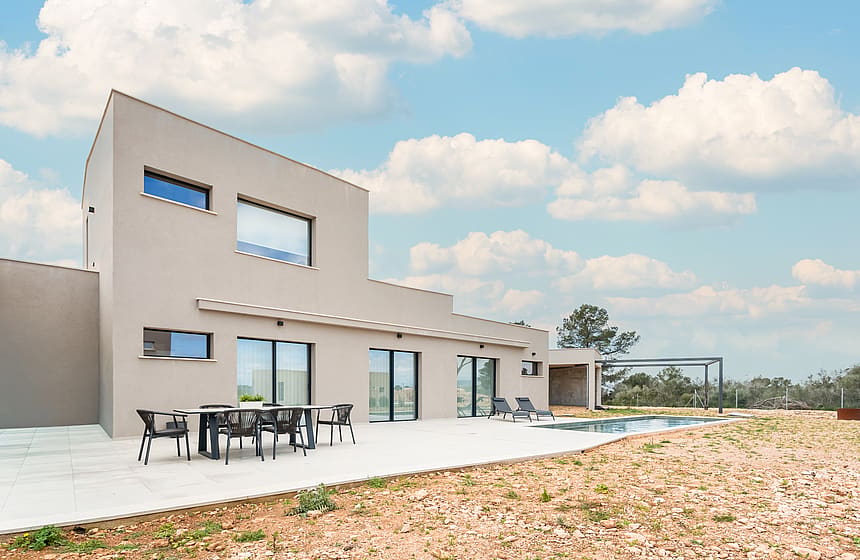 Exterior view of a contemporary villa in Son Gual featuring a concrete facade, swimming pool, and outdoor dining area.