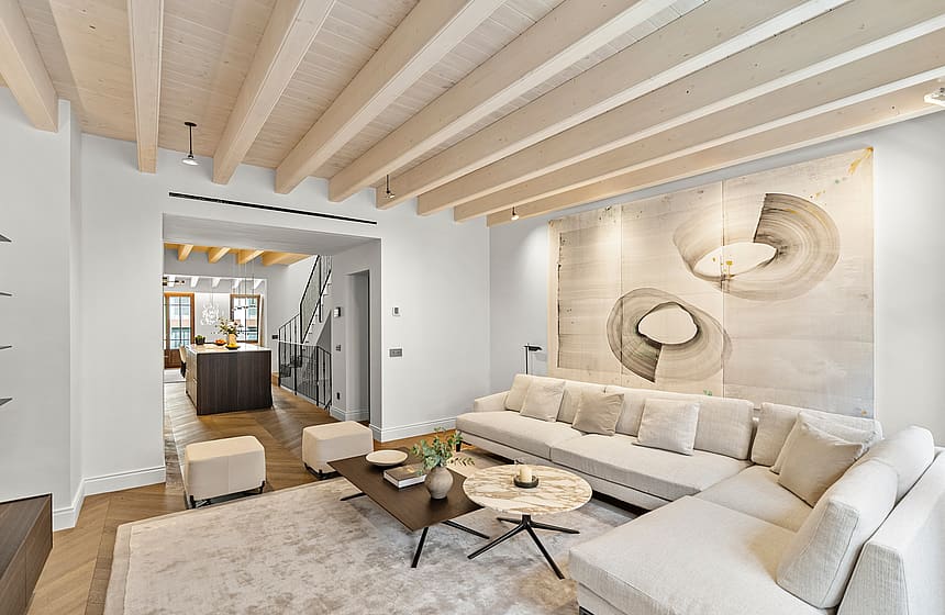 Contemporary living room featuring light wood ceiling beams, herringbone oak flooring, and neutral-toned furniture.
