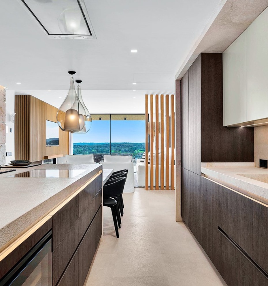 Modern kitchen with dark wood cabinetry, a stone kitchen island, and a clear view towards mountain scenery in Santa Ponsa.